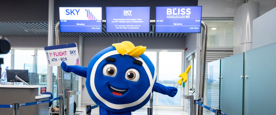 La mascotte de l’aéroport avec une pancarte pour le premier vol vers Barcelone